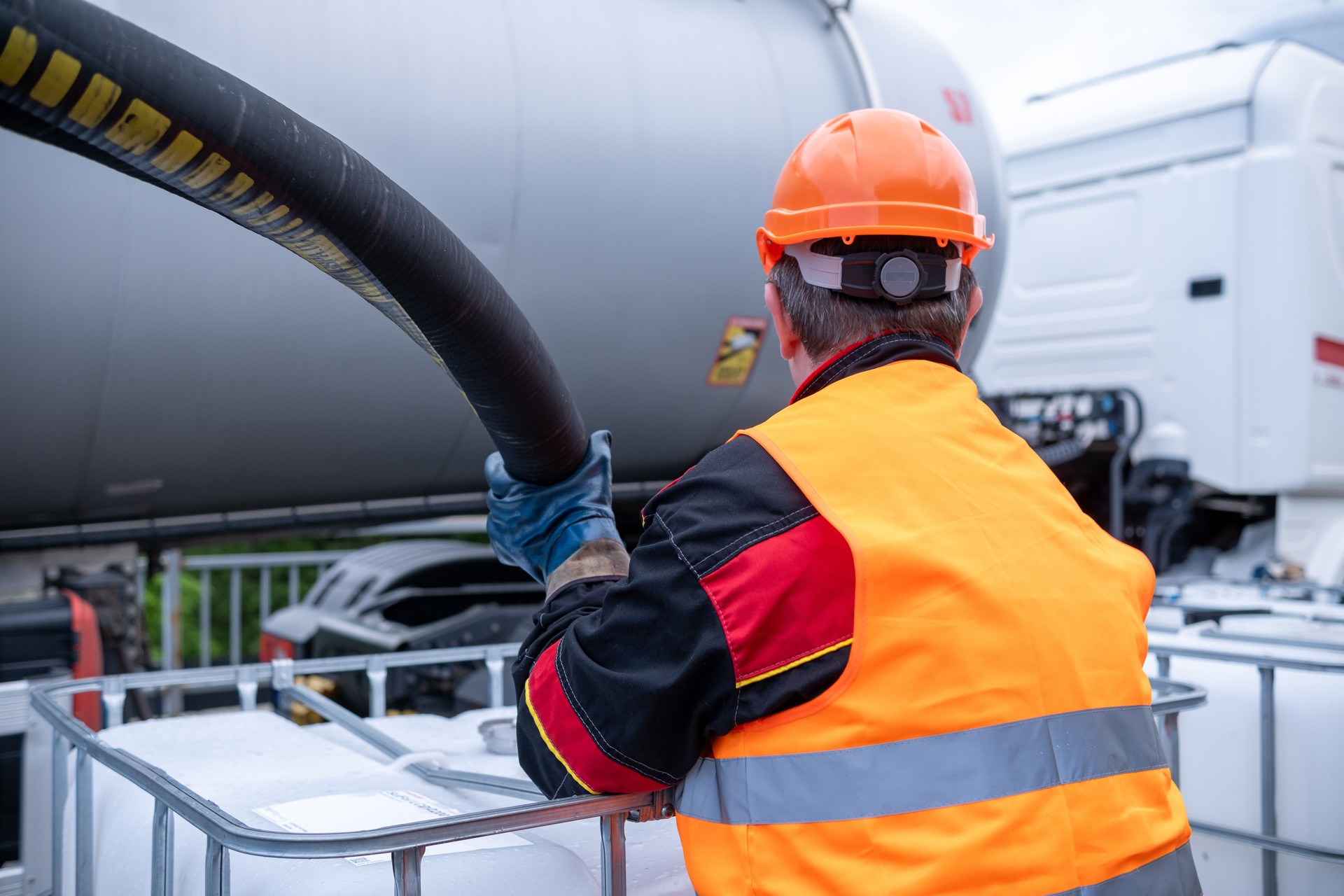 A technician transfers oil from a tanker into a 1000-liter IBC Bulk Container.